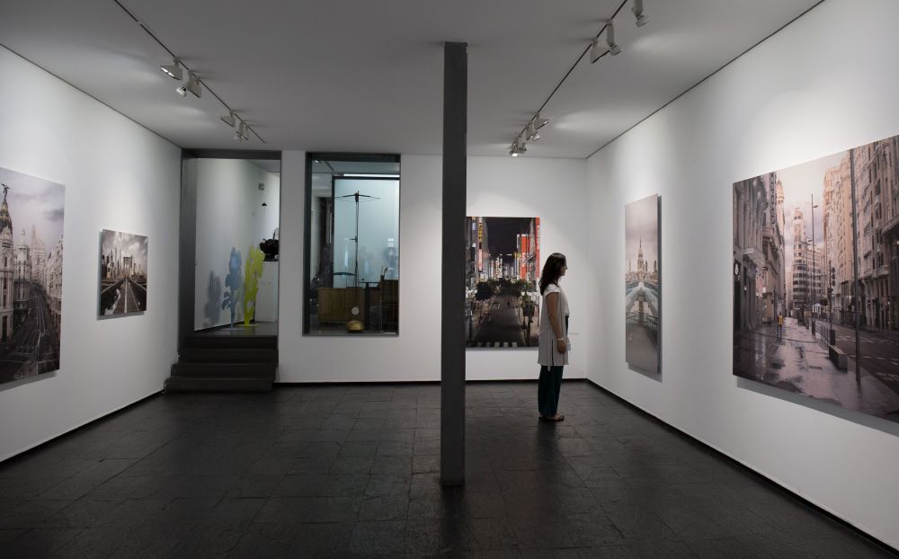 Visitante contempla pinturas de arte contemporáneo en una galería